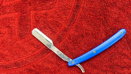 Close-up a classically styled straight razor on red towel. Barbershop concept.