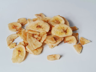 Dried banana chips on a light grey background.