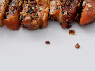 Raw uncooked pork belly portions in soy sauce marinade on a light grey surface.