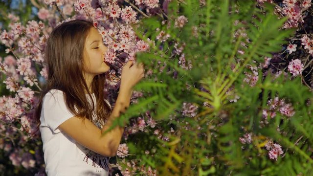 White young Woman walks in the park with a spring background Sonchus Canariensis Boulos in the foreground with Red Blooming Buds shot URSA 4.6K
