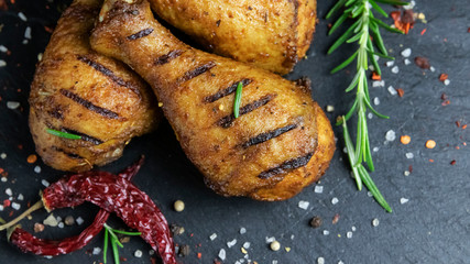 grilled chicken legs with red sauce on a black stone surface