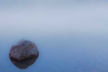 Stone inside the water in a blue lake