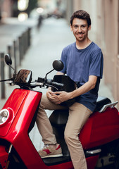 Close up of Smiling Biker boy with black helmet sitting on red motorcycle