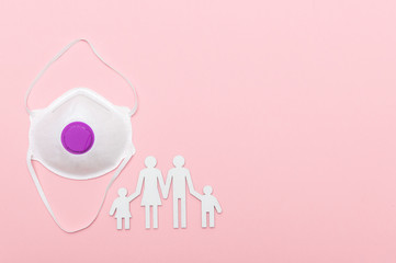 Cardboard figures of the family  and mask on pink background. Coronavirus or Covid-19 virus concept
