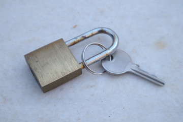 A padlock next to the key that opens it on a weathered gray marble surface