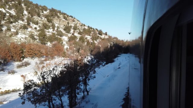 Snowy Mountains, hillsides, forests, train travel in the steppes. it passes through railway stations in the mountain village. watching the journey through the window of the wagon