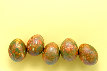 modern trendy marble Easter eggs of the original color on a yellow background closeup with a place for text.