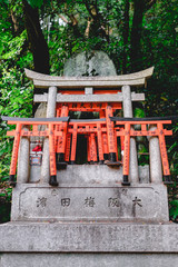 Wooden and stone torii gates and rock with kanjis at sanctuary in Fushimi Inari taisha shrine, Kyoto