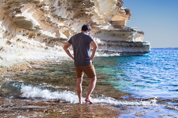 Summer vacation joyful man standing in the sea enjoying the clear water and beautiful cliff view. il hofra I Kbira