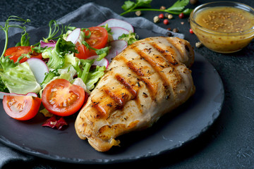 grilled chicken fillet with vegetable salad on a dark background