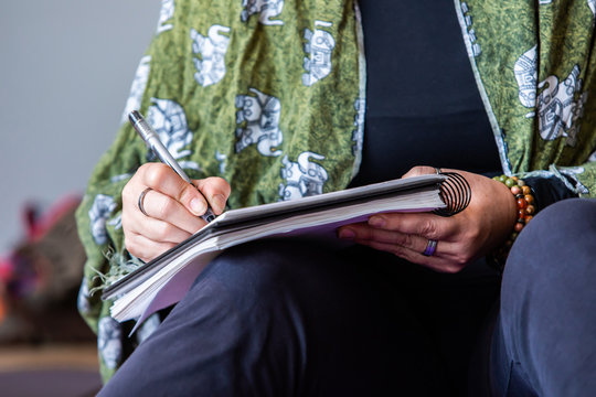 The yoga trainer who holds a notepad in her hands and makes some notes. Close up photo of a lady making notes during the yoga class