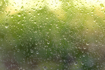 Raindrops on fogged glass are illuminated by the first rays of the sun after bad weather. Soft focus.