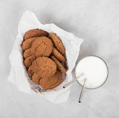 Oatmeal cookies in a box with milk on a light background top view