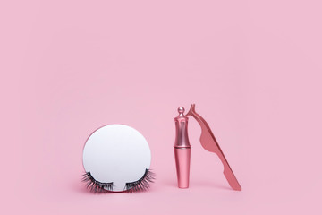 Magnetic fake eyelash in mirror kit, eye liner, tweezers isolated on pink background. Eyelash...