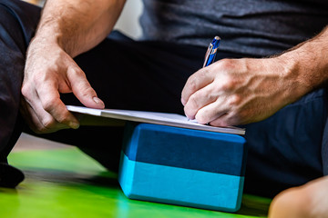 The man writing something about yoga on a copybook. The man learning a new things and making some...