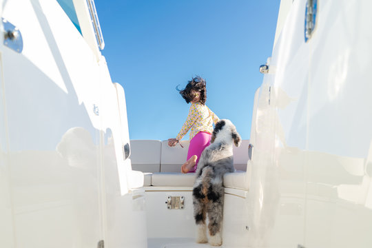 Young girl on the bow of a boat with her puppy during summer