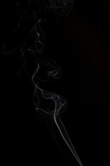Delicate column of smoke from incense stick isolated on black background, selective focus