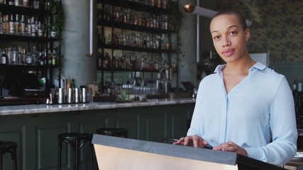 Portrait of female owner of restaurant bar standing by counter checking reservations before service - shot in slow motion