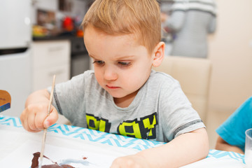 Little boy draws a brush and paint in the nursery