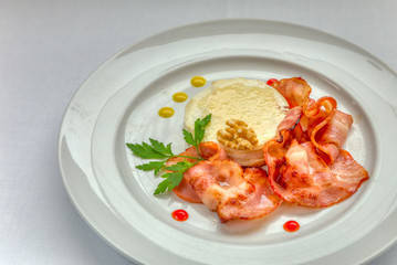 Warm goat cheese with honey and bacon served on a white dish