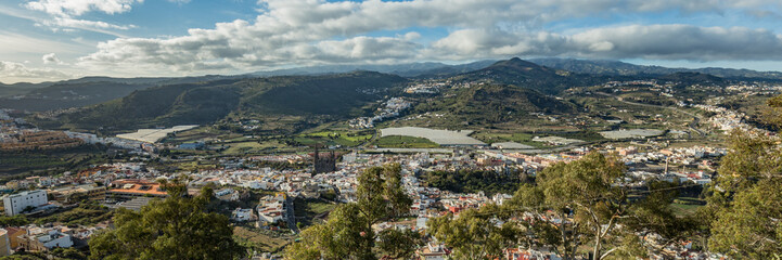 Fototapeta na wymiar Super wide panorama. Aerial view of historic town Arucas with impressive cathedral. Warm sunny day, bright blue sky and beautiful white clouds. Gran Canaria, Canary islands, Spain