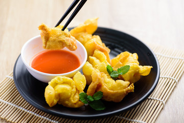 Deep-fried crispy wonton stuffed with minced pork, quail egg and shrimp eating with chili sauce by using chopsticks, Asian food	