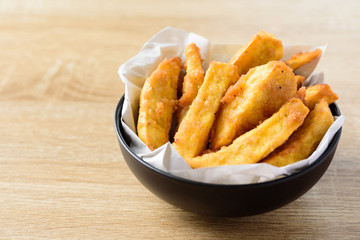 Deep-fried sweet potato in a bowl on wooden table, Delicious homemade snack