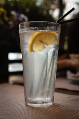 background. transparent glass of lemonade with ice and lemon. black tube in a glass.