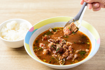 Traditional Northern Thai food, spicy Thai curry soup with beef guts (Kaeng Om Nua) in a bowl eating by spoon