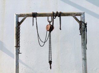 Old steel reel with chains for lifting and hoisting stuff to higher floor hung on iron beam beside...