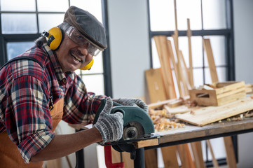 Carpenter working on woodworking machines in carpentry shop, wooden product
