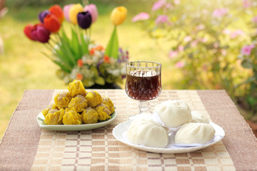 Chinese Steamed pork Buns and dumpling with crystal glass beverage are on the table among vintage garden background.light meal at afternoon.selective focus.