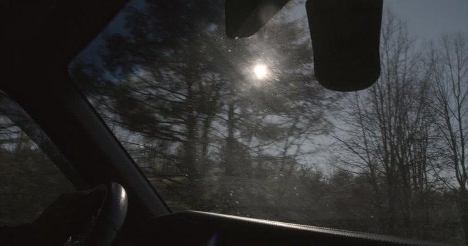 Slow motion driving in rural North Carolina with the sun flickering through trees. View out windshield and trees.