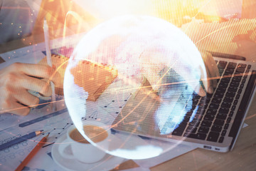 Double exposure of businessman working on laptop on background. International business hologram in...