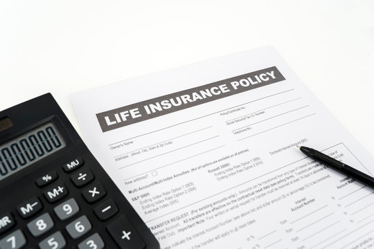 Closeup of life insurance document near calculator