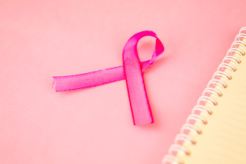 Closeup of pink ribbon besides a notebook
