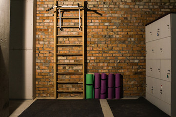 wooden swedish ladder, yoga mats and metal locker in the office gym  