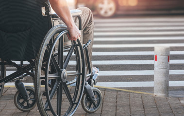 Disablee man on wheelchair crossing the road.