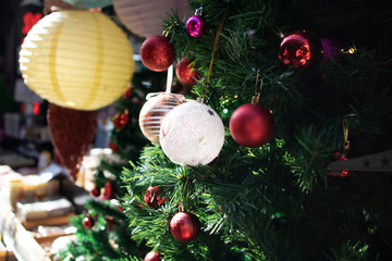 Decorative Christmas decorations close-up. Hanging ornaments on the fake pine tree. There are colored balls on it.