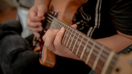 Fototapeta na wymiar Cropped shot of male musician playing guitar in music instrument