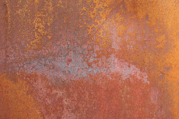 A abstract photograph of rusty metal with patterns on it with orange, brown, and bluish coloring.