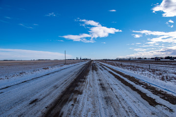 Fototapeta na wymiar Vanishing point - Gravel road on the prairies in winter, Alberta, Canada