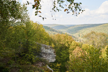 The Minister Creek Trail overlook in Allegheny National Park. In the distance can be seen the hills, mountains, valleys, and forests of the park. In the foreground is a large stone boulder.