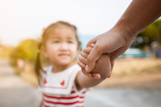 Parent and asian child girl holding hand together with love and care