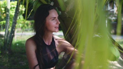 Peaceful Woman Spending Time at Exotic Seaside. Carefree Caucasian Girl in Bikini Sitting under Coco Palm at Tropical Coastline. Koh Phangan Island, Thailand.