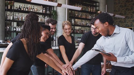 Male restaurant bar manager with digital tablet giving motivational talk to waiting staff before opening - shot in slow motion