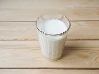 Glass cup full of milk on a wooden surface. White cow's milk