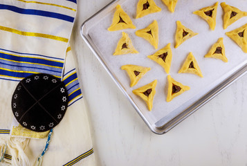 Raw hamantaschen cookies on baking tray with kippa and tallit.