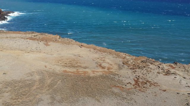 Drone circling tourist taking pictures in desert cliffs and beach in Maui, Hawaii