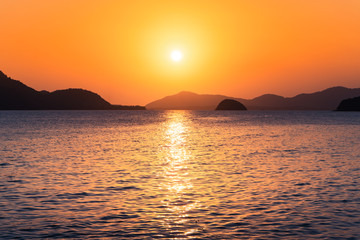 Naklejka premium The ship in the evening sea, beautiful golden light